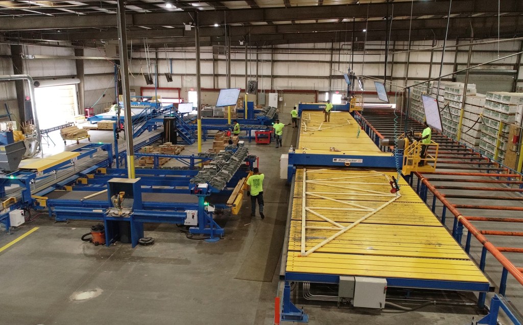 Automated Solutions Off-Site Construction - A wooden roof truss is being assembled using an automated process