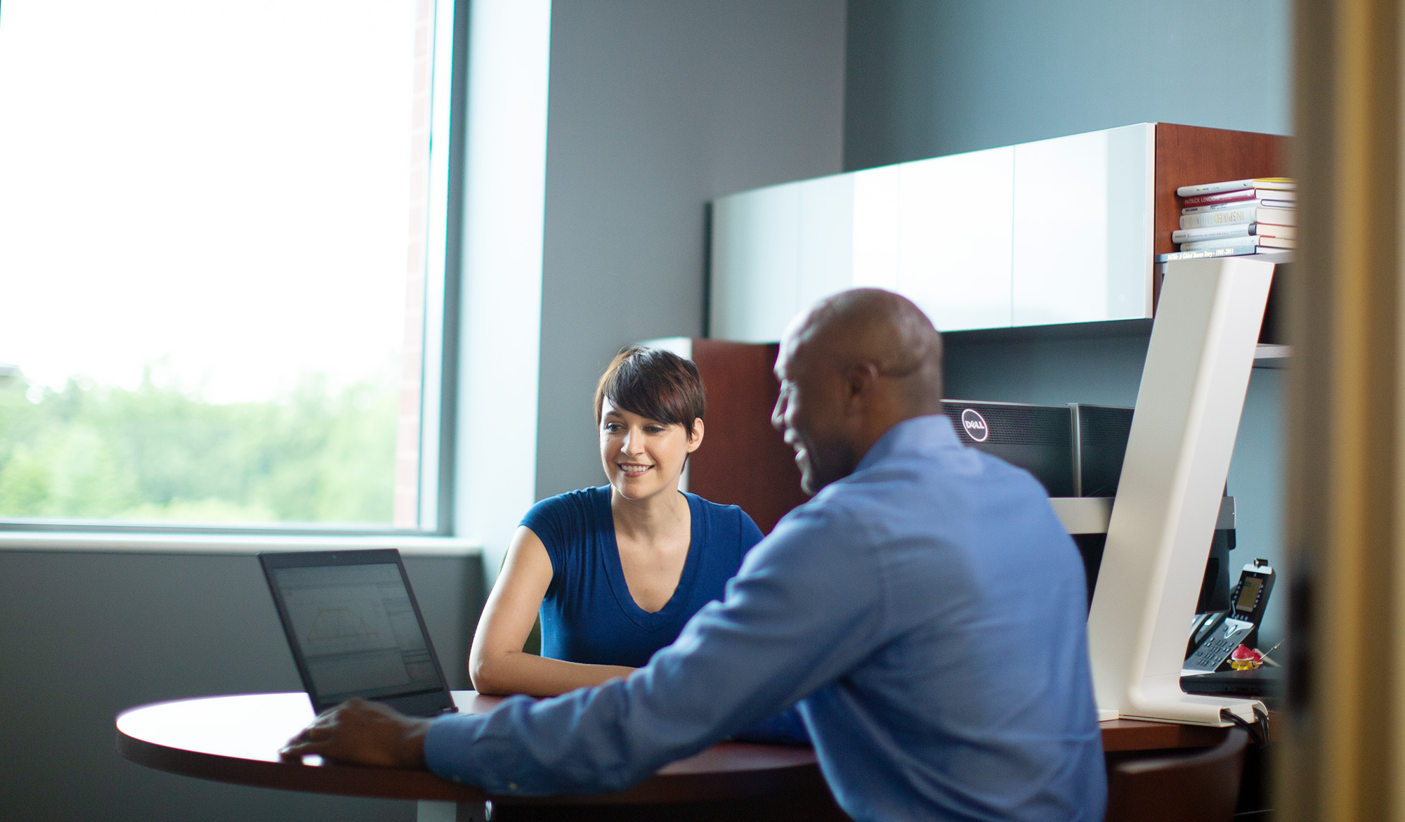 Contact MiTek - Woman and man sit at a desk collaborating on a laptop