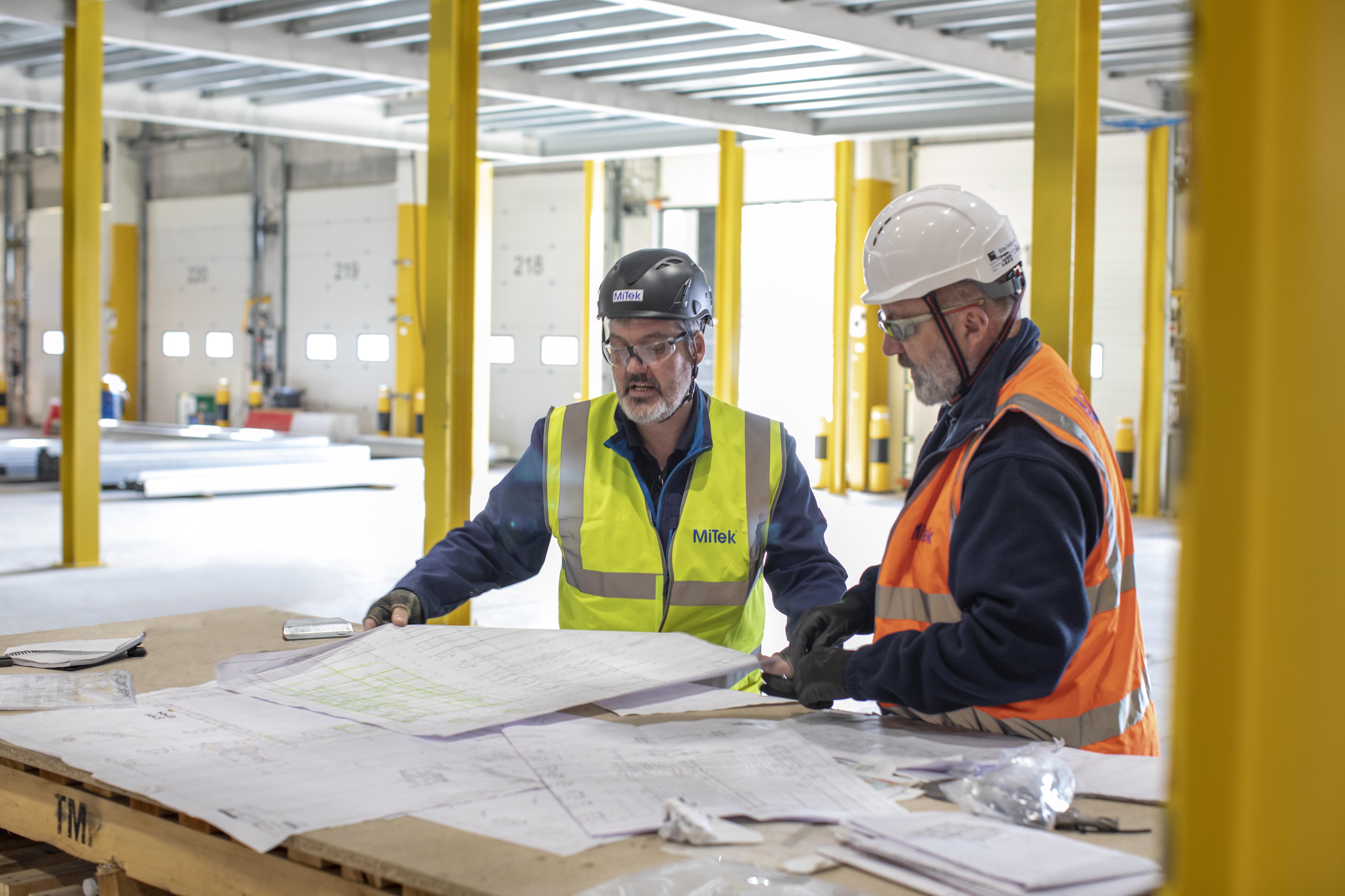 Men in hardhats consulting building plans on construction site.