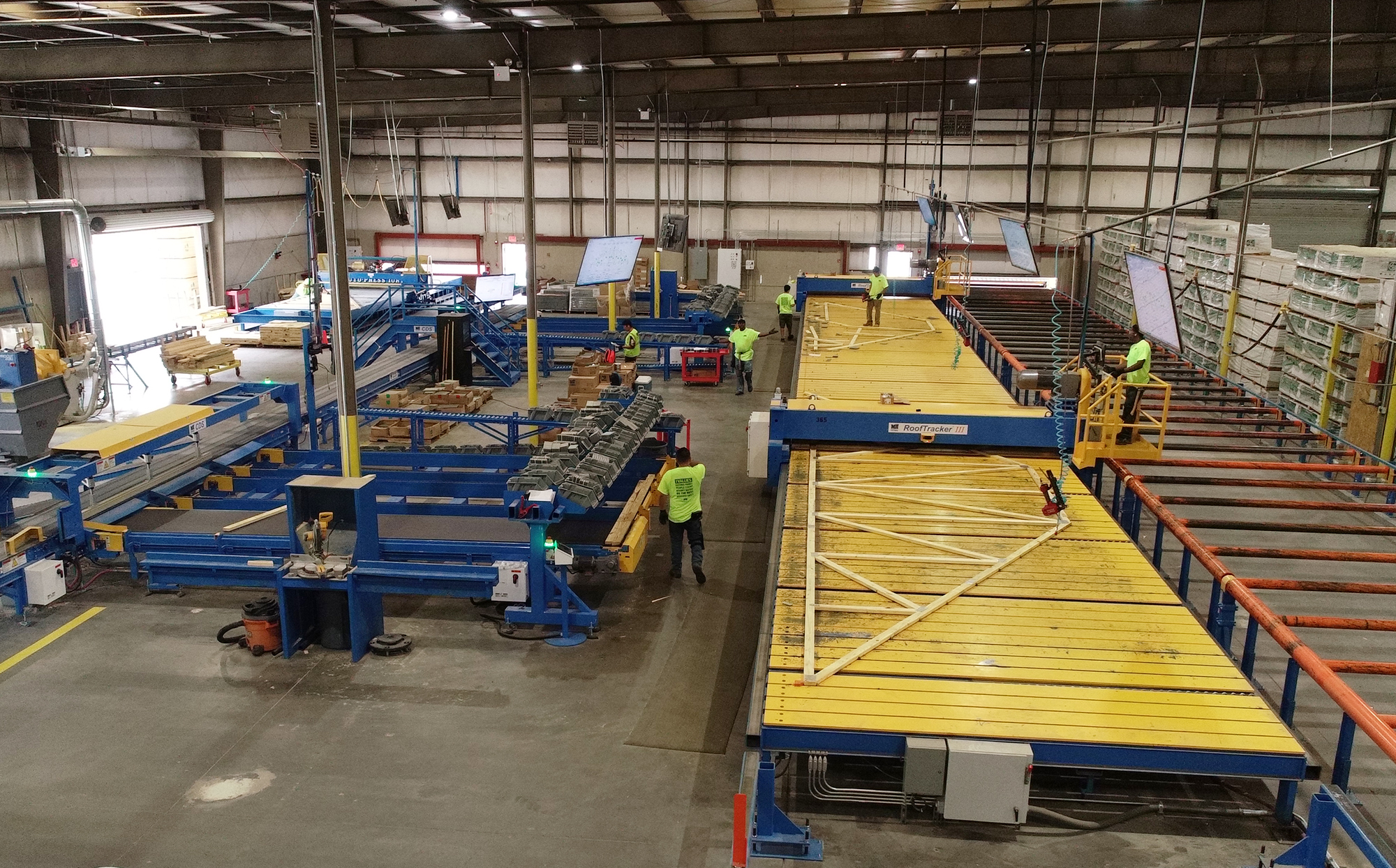 Solutions automatisées Construction hors site - Une ferme de toit en bois est assemblée à l'aide d'un processus automatisé.