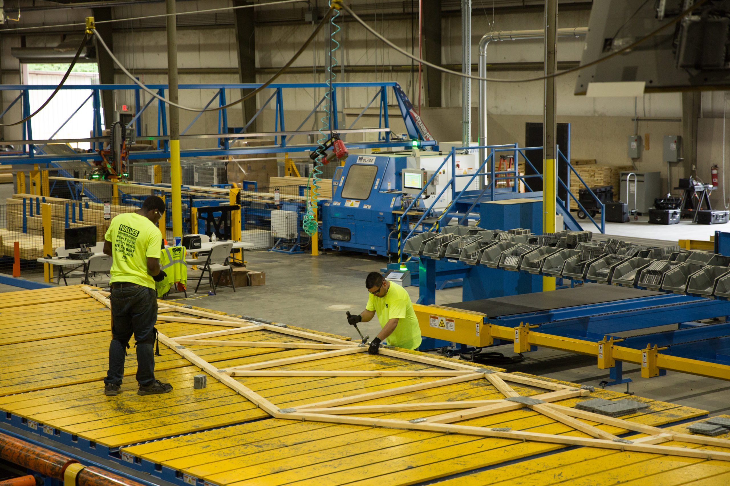 Design Make Build Off-Site Construction - Two workers assemble a wooden roof truss